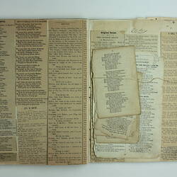 Open scrapbook page with clipping of poems stuck to page and extra clippings on top of page.