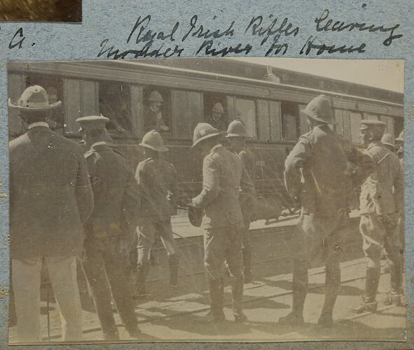 Group of soldiers standing next to train.