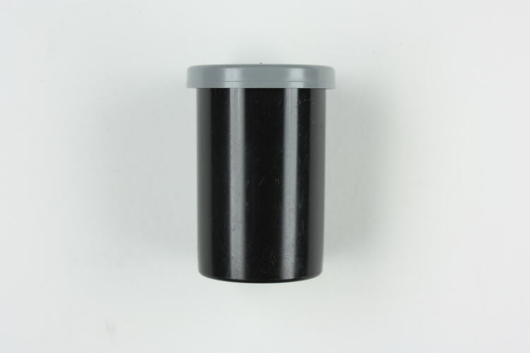 Black plastic canister with grey plastic lid.