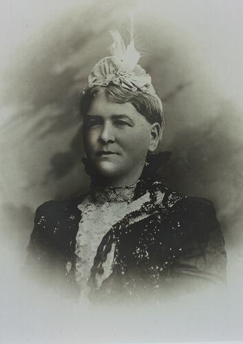 Elderly woman with ornate lace top and feathered headpiece