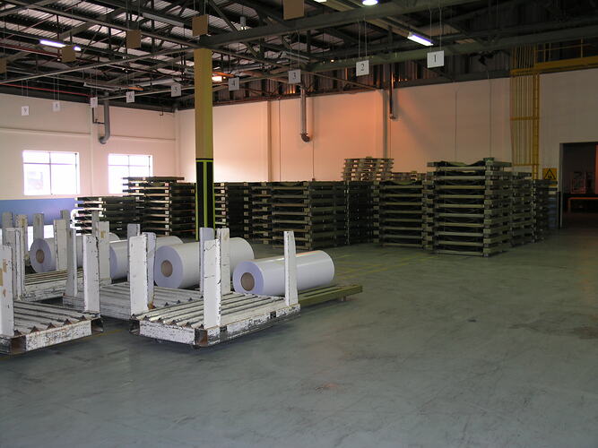 Paper rolls and pallets in warehouse.
