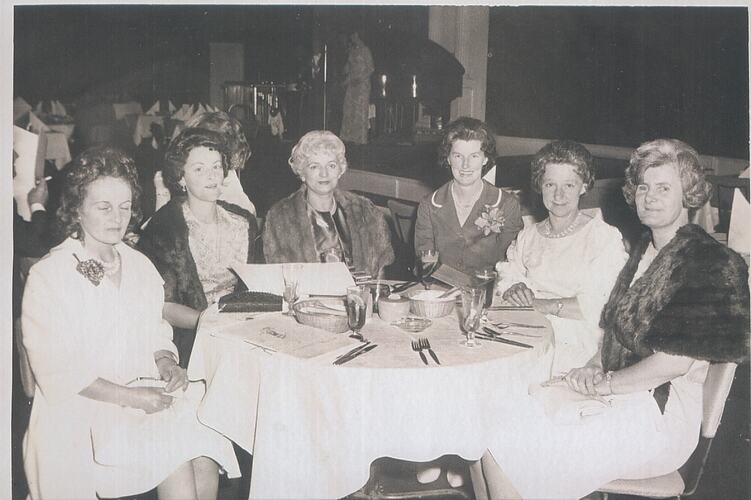 Six women seated around dining table.