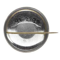 Metal back of round badge with horizontal pin attachment.