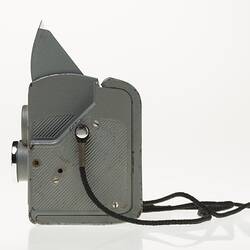 Grey metal camera with cord. Left profile.