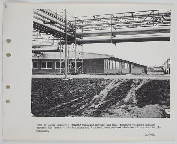 Exterior of building with pipes and overhead walkway.