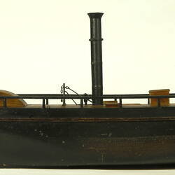 Side view of wooden paddle steamer model.