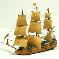 Three quarter view of three masted ship with wooden hull.