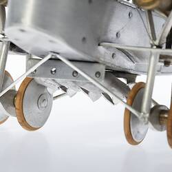 Model of a bi-plane made mostly of aluminium sheet metal. Detail view of two pairs of wheels.