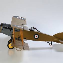Model biplane aeroplane painted mustard brown with grey engine. Left side view.
