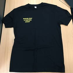 Black tshirt with yellow text in top right hand corner.