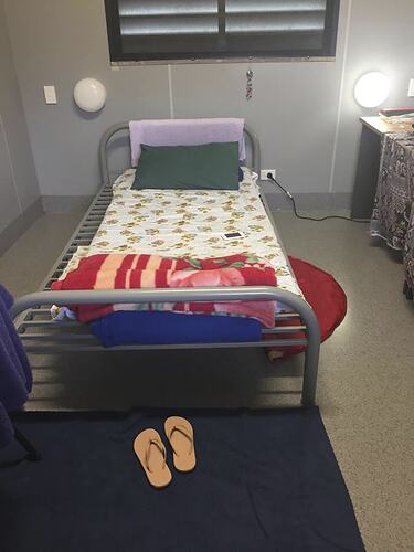 Metal bed with thongs on floor at bed end.