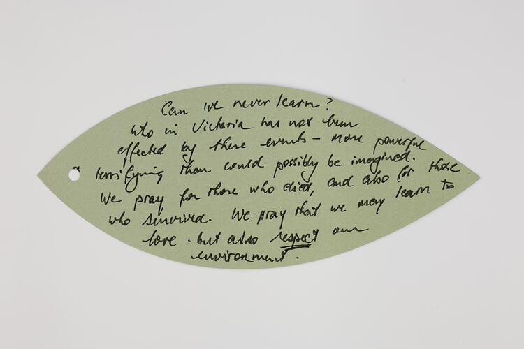 Green paper leaf with handwritten text in black ink.