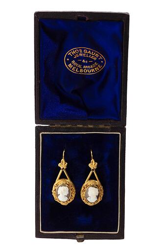 Gold mounted cameo earrings. Round white cameo profile bust with brown background. Navy box.