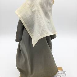A doll dressed as a nun in a grey dress and white veil