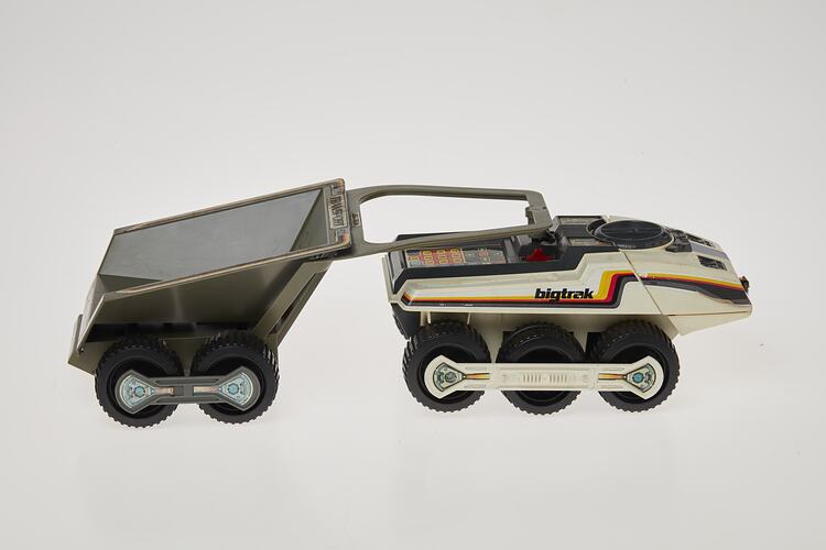 Cream six-wheeled toy truck with grey two-wheeled trailer. Stickers on sides. Right profile.