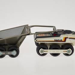 Cream six-wheeled toy truck with grey two-wheeled trailer. Stickers on sides. Right profile.