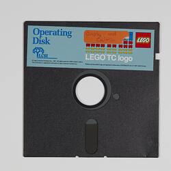 Black floppy disk with hole in centre. Has blue, red and yellow LEGO label along top edge.