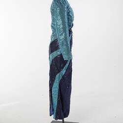 Aqua full-length sequin dress with navy swirls. Long sleeves, high neckline. Right profile.