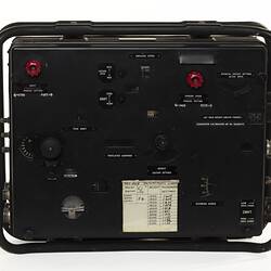 Black electronic box with white print. Has red and black dials and a white text label.