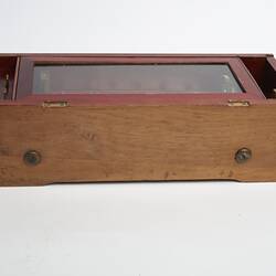 Wooden rectangular box. Glass section on top on box. Side view.