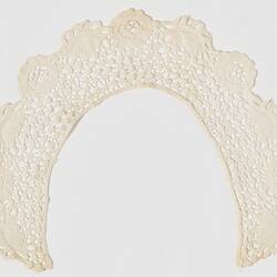 Back of semi-circular cream lace collar with a waterlily design. Scalloped edges.