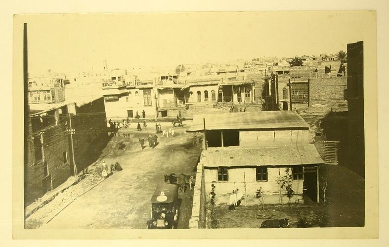 Elevated view of a village street with people and a car.