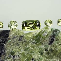 Raw green mineral, with five polished green gems above.