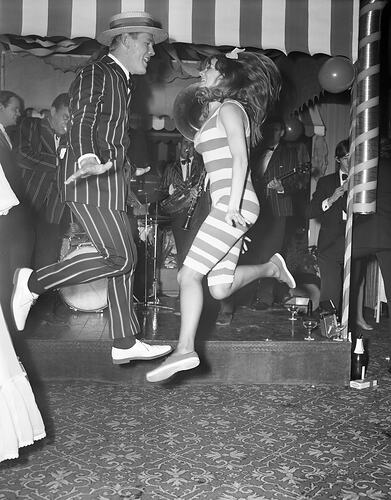 Man and woman dancing in striped costumes.
