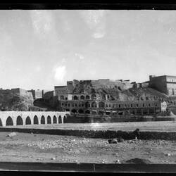 Ruins of ancient city with arched bridge.