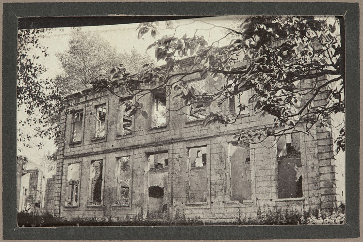 Damaged stone building surrounded by trees.