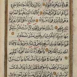 Page from the Qur;an with black lettering and gold border.