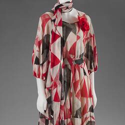 White, red, and black pattered dress with neck-scarf.