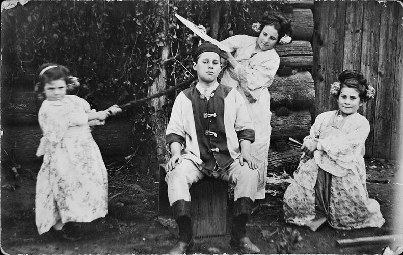 Four children, three girls and a boy, dressed in fancy costumes.