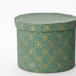 Round green and gold patterned hat box.