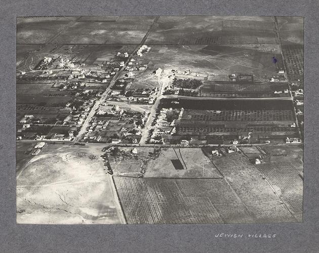 Aerial view of cultivated land and a collection of buildings and streets.