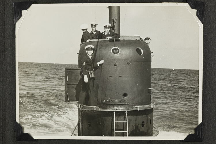Four men on standing on tower of submarine.