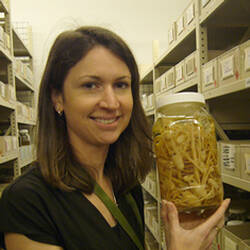 Woman in collection store holding a jar of crustaceans.