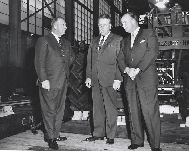 3 men standing in front of machine.