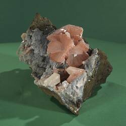 Grey rock with pink crystals on one surface.