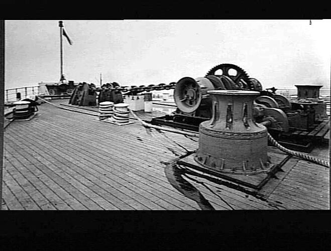 Ship deck with forecastle deck anchor cable sheave and windlass.