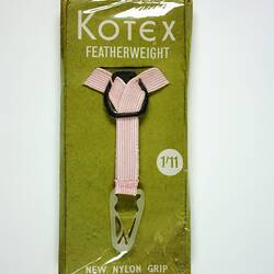 Pink y-shaped belt in plastic wrap on green card