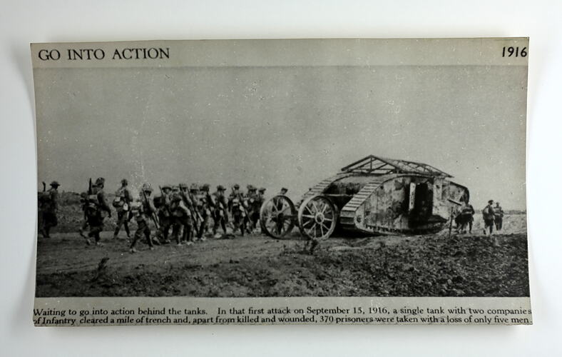 Curled photograph of tank surrounded by soldiers.