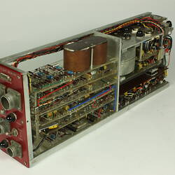 Red control panel with knobs and dials on front of metal box. Case removed to show internal wires and components.